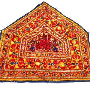 Könnte beinhalten: Ein farbenfroher, dreieckiger Wandbehang mit aufwendigen Stickereien und Spiegelarbeiten. Das Design zeigt ein zentrales Motiv einer Gruppe von Figuren in Rot, Blau und Gelb, umgeben von einem Rand aus Blumenmustern und geometrischen Formen.