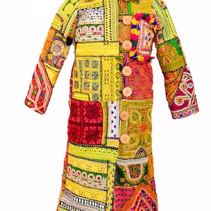 Könnte beinhalten: Ein langer, bunter Patchwork-Mantel mit Knopfleiste. Der Mantel besteht aus verschiedenen Stoffen und ist mit aufwendigen Stickereien und Verzierungen versehen. Der Mantel ist ein lebendiges Zusammenspiel aus Gelb, Rot, Grün, Blau und Lila.