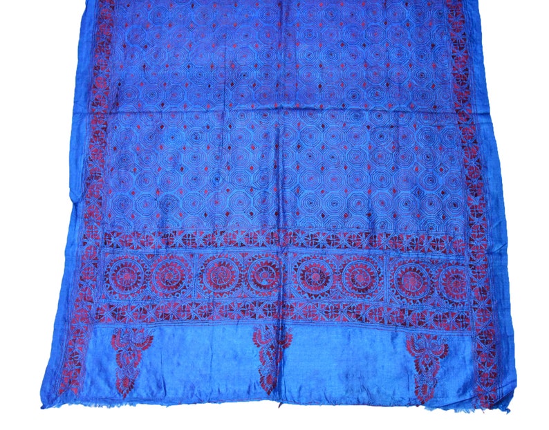 May include: A blue silk scarf with intricate red embroidery. The embroidery features a repeating geometric pattern and a border of floral motifs.