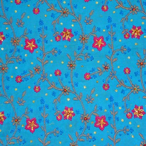 May include: A blue fabric with a floral pattern embroidered with pink and gold flowers. The fabric is covered in small gold and blue sequins.