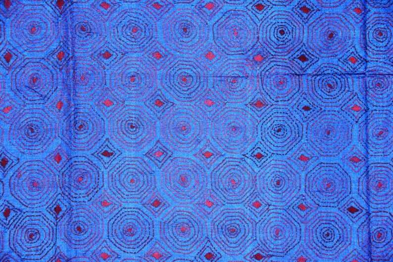 May include: Blue fabric with a repeating pattern of red concentric circles and diamonds.