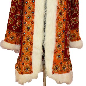 May include: A long, red and orange coat with a white fur trim. The coat is covered in intricate embroidery and sequins.