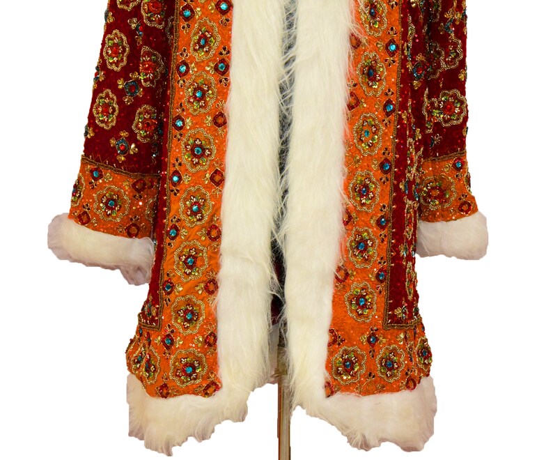 May include: A long, red and orange coat with a white fur trim. The coat is covered in intricate embroidery and sequins.