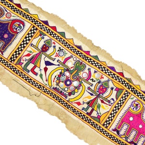 May include: A colorful fabric banner with a repeating pattern of stylized figures and elephants. The banner is decorated with small mirrors and has a frayed edge.