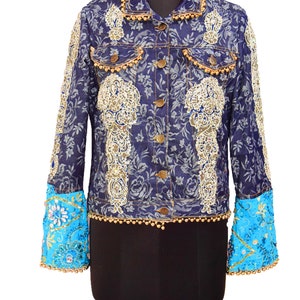 Könnte beinhalten: Eine blaue Jeansjacke mit goldener Stickerei und Perlenbesatz. Die Ärmel sind aus türkisfarbenem Stoff mit goldener Stickerei und Perlen.
