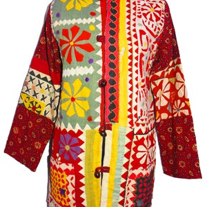 May include: A long-sleeved patchwork jacket with a colorful floral design. The jacket has a button closure and a pocket on the front. The fabric is a mix of red, yellow, green, and white.