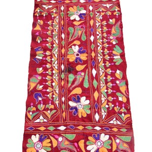 Könnte beinhalten: Rechteckiger, weinroter Stoff mit aufwendiger Stickerei. Das Design zeigt große, stilisierte Blumen in Weiß, Gelb und Lila, zusammen mit grünen Blättern und geometrischen Mustern. Die Kanten sind mit einem dekorativen Rand versehen.