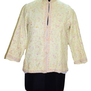 Könnte beinhalten: Eine hellgelbe bestickte Jacke mit Stehkragen und Blumenmuster. Die Jacke hat einen Knopfverschluss und lange Ärmel.