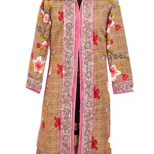 Könnte beinhalten: Eine lange braune Jacke mit rosa und silbernem Besatz. Die Jacke hat einen Blumendruck und einen Reißverschluss.