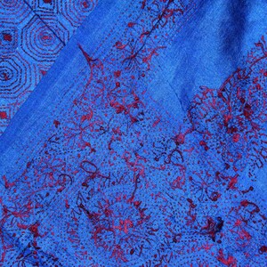 May include: A blue fabric with a red embroidered pattern. The pattern is a combination of geometric shapes and floral designs.