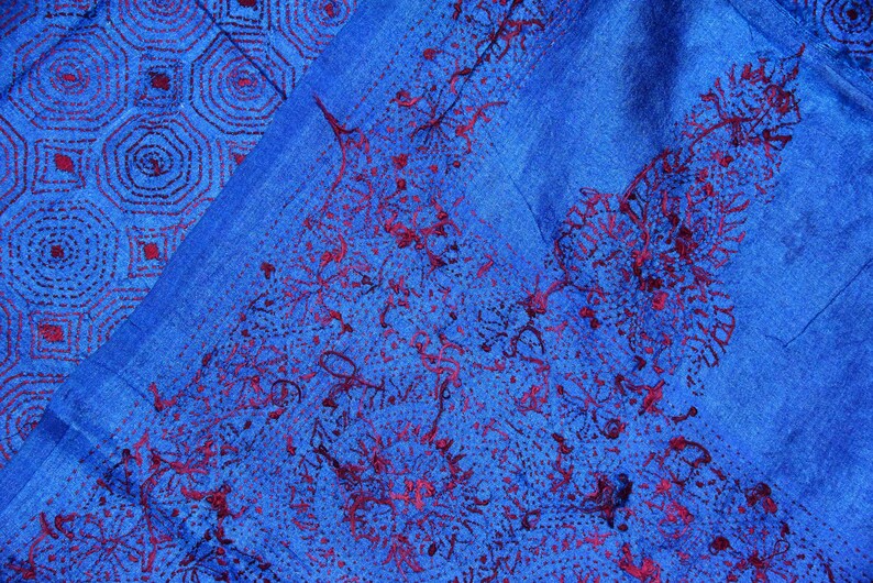 May include: A blue fabric with a red embroidered pattern. The pattern is a combination of geometric shapes and floral designs.