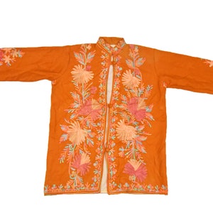May include: A long-sleeved orange jacket with a mandarin collar and floral embroidery. The jacket is made of a soft, lightweight fabric and has a relaxed fit.