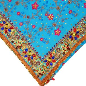 May include: A turquoise blue fabric with a gold and colorful beaded trim. The fabric has a floral pattern with small pink flowers and gold accents.