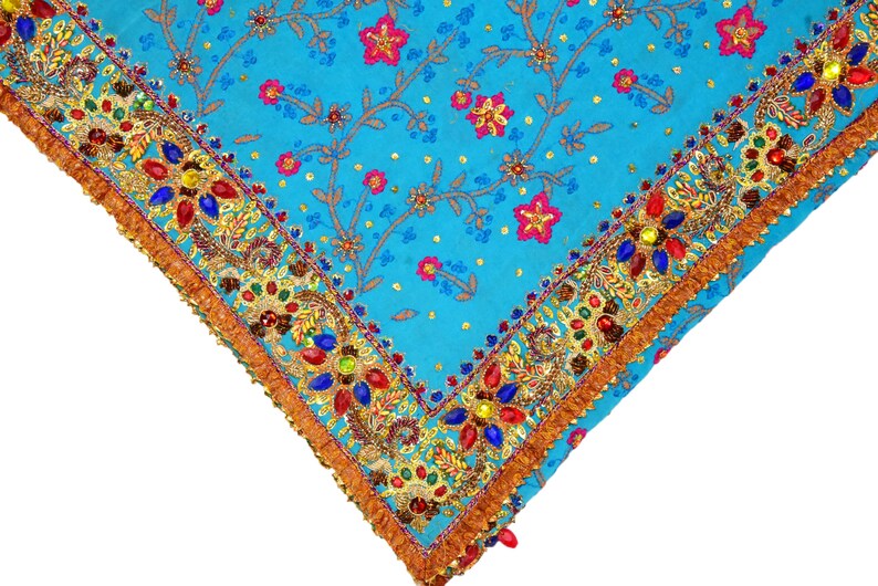 May include: A turquoise blue fabric with a gold and colorful beaded trim. The fabric has a floral pattern with small pink flowers and gold accents.