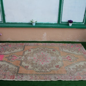 May include: A vintage-style rug with a faded pink and beige color scheme. The rug has a central medallion design with intricate floral patterns.