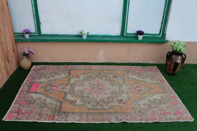 May include: A vintage-style rug with a faded pink and beige color scheme. The rug has a central medallion design with intricate floral patterns.