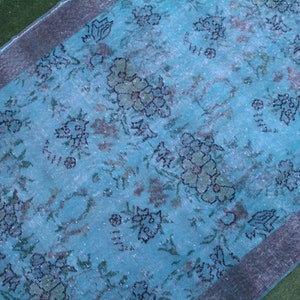 Pu&ograve; includere: Un tappeto vintage color turchese con un motivo floreale. Il tappeto ha un bordo argentato ed &egrave; realizzato in un materiale morbido e tessuto.