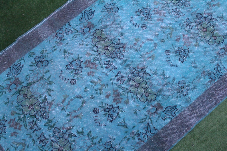 Pu&ograve; includere: Un tappeto vintage color turchese con un motivo floreale. Il tappeto ha un bordo argentato ed &egrave; realizzato in un materiale morbido e tessuto.