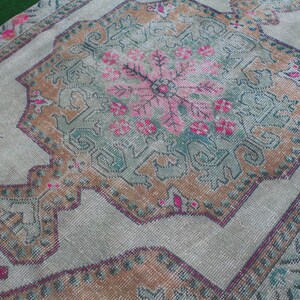 Puede incluir: Una alfombra vintage con un patr&oacute;n floral descolorido en tonos de rosa, marr&oacute;n y verde. La alfombra tiene un aspecto desgastado y est&aacute; hecha de un material suave y tejido.