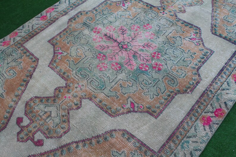 Puede incluir: Una alfombra vintage con un patr&oacute;n floral descolorido en tonos de rosa, marr&oacute;n y verde. La alfombra tiene un aspecto desgastado y est&aacute; hecha de un material suave y tejido.