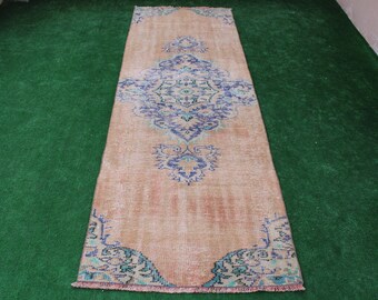May include: A vintage runner rug with a faded pink background and a blue and green floral pattern. The rug has a fringed edge.