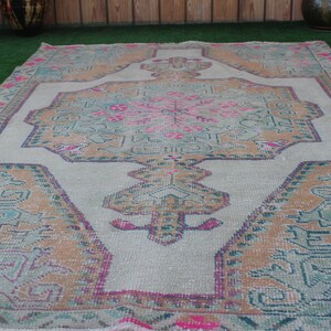 Puede incluir: Una alfombra vintage con un patr&oacute;n floral descolorido en tonos rosa, azul y marr&oacute;n. La alfombra tiene un fondo blanco y un aspecto desgastado.