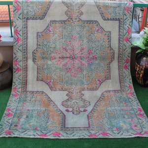 Puede incluir: Una alfombra vintage con un patr&oacute;n floral descolorido en tonos de rosa, verde y beige. La alfombra tiene un fondo blanco y un borde geom&eacute;trico.