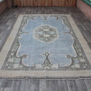 May include: A light blue rug with a beige border and a floral pattern. The rug has a faded, vintage look.