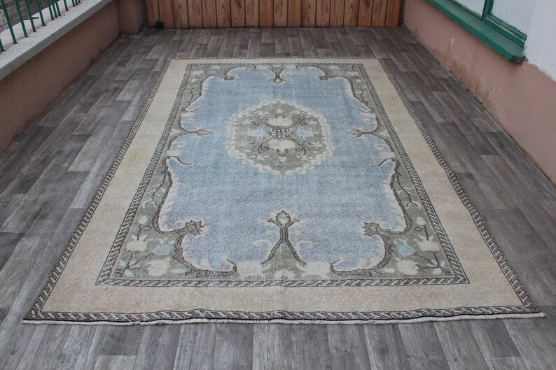 May include: A light blue rug with a beige border and a floral pattern. The rug has a faded, vintage look.