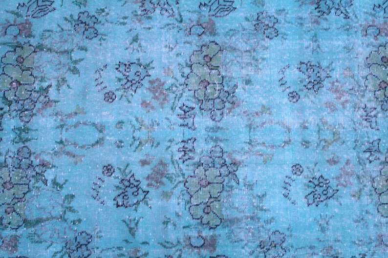 Pu&ograve; includere: Un tappeto vintage con sfondo blu e un motivo floreale in tonalit&agrave; di verde e nero.