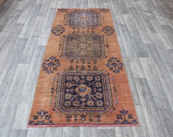 May include: A vintage runner rug with a faded orange background and intricate blue and green floral patterns. The rug has a distressed look and is perfect for adding a touch of bohemian style to any room.