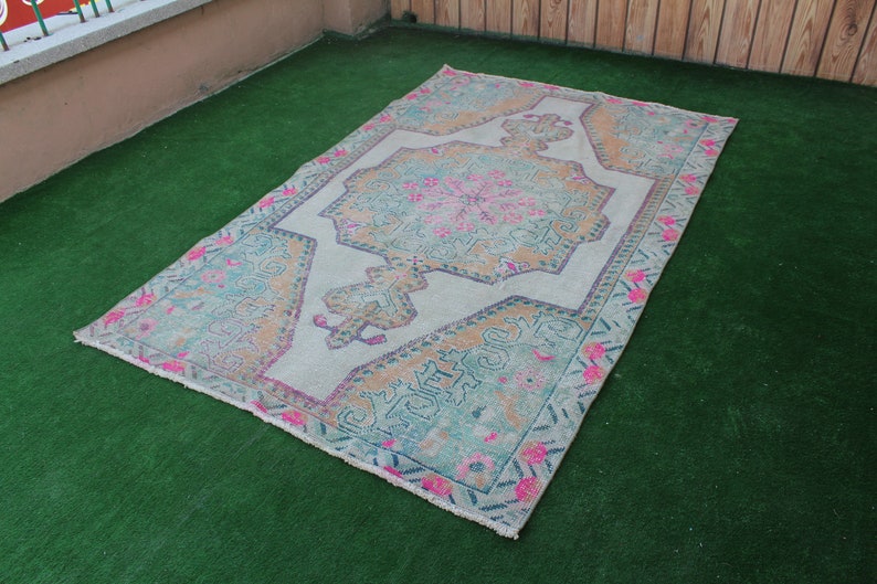 Puede incluir: Una alfombra turca vintage con fondo blanco y un colorido patr&oacute;n floral en tonos rosa, azul y naranja. La alfombra tiene un aspecto desgastado y es perfecta para a&ntilde;adir un toque de estilo bohemio a cualquier habitaci&oacute;n.