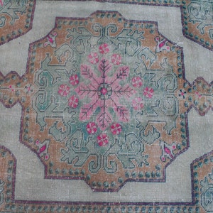 Puede incluir: Una alfombra vintage con un dise&ntilde;o central de medall&oacute;n que presenta un patr&oacute;n floral en tonos de rosa, verde y marr&oacute;n. La alfombra tiene un fondo beige claro y un borde con un patr&oacute;n geom&eacute;trico repetitivo.