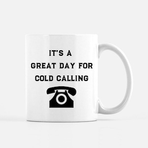 May include: White ceramic mug with a black handle. The mug features the text "IT'S A GREAT DAY FOR COLD CALLING" in black, along with a black telephone graphic. The mug is designed for beverages.