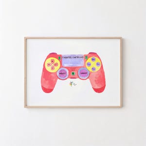May include: A framed watercolor illustration of a red video game controller. The center touchpad reads FINANCIAL CONTROLLER, with buttons labeled DEBIT and CREDIT. The directional pad is yellow with plus and minus signs, and action buttons are yellow.