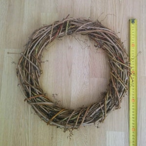May include: A brown twig wreath with a diameter of approximately 30 cm. The wreath is made of natural twigs and is perfect for decorating for the holidays or for everyday use.