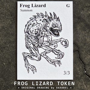 May include: A rectangular white game card featuring a black ink illustration of a spiky, sharp-toothed creature. The text reads Frog Lizard, Summon, G, and 3/3. The card is labeled with the text Frog Lizard Token and Original Drawing by Xaxabel.