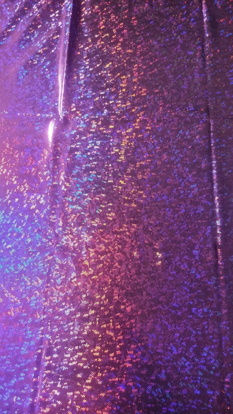 Puede incluir: Primer plano de una tela iridiscente con un esquema de color morado, azul y rosa. La tela tiene una superficie texturizada y brillante.