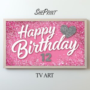 May include: A rectangular framed digital display featuring a pink glitter background with the white text Happy Birthday and the number 12 in silver glitter. A silver glitter heart is positioned to the right of the text. The frame is light wood.