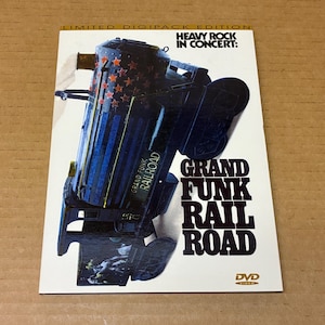 Może przedstawiać: Pudełko DVD z napisem "GRAND FUNK RAILROAD" w kolorze białym. Okładka przedstawia stylizowaną lokomotywę z czerwonymi gwiazdkami i niebieskimi paskami. Widoczny jest również tekst "HEAVY ROCK IN CONCERT".