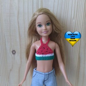 May include: A doll wearing a watermelon-patterned crochet halter top, denim shorts, and white shoes. The doll has blonde hair and blue eyes. The image includes the text "Made with love from Ukraine" with a heart and the Ukrainian flag.