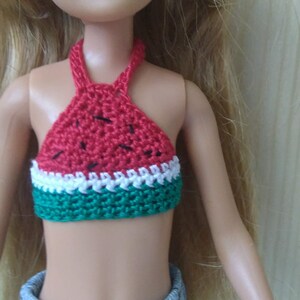May include: A red, white and green crocheted halter top with a watermelon design. The top is made of yarn and has a halter neck style.