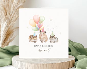 May include: A square greeting card featuring a watercolour illustration of three hamsters wearing colourful party hats. The hamsters are positioned below a cluster of pastel-coloured balloons and small stars. The text reads HAPPY BIRTHDAY Harriet.