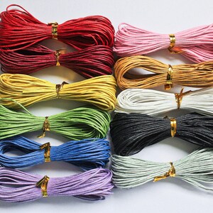 May include: Eleven spools of colorful waxed cotton cord, numbered 1 through 11. The cords are arranged in rows, with each spool tied in a bow.