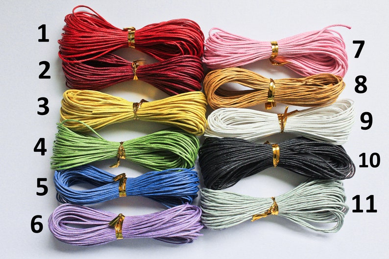May include: Eleven spools of colorful waxed cotton cord, numbered 1 through 11. The cords are arranged in rows, with each spool tied in a bow.