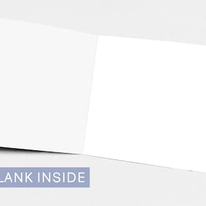 May include: An open, blank greeting card with a white interior. The card is displayed on a light gray surface. The text "BLANK INSIDE" is printed in white on a light blue rectangular label.