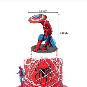 Puede incluir: Un adorno para tarta de Spider-Man, de 16 cm de altura, sosteniendo el escudo del Capit&aacute;n Am&eacute;rica. El personaje rojo, azul y negro est&aacute; sobre una base gris. La tarta es roja con glaseado blanco en forma de telara&ntilde;a y un gr&aacute;fico de ara&ntilde;a negra.