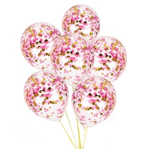 May include: A bouquet of six clear balloons filled with pink and gold confetti. The balloons are tied together with gold ribbon, creating a festive and celebratory look. Perfect for parties and special events.
