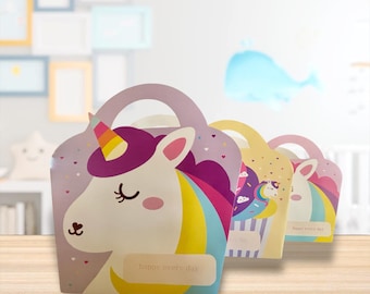 May include: A row of colorful unicorn-themed gift boxes with handles. The lead box features a unicorn with a rainbow mane and horn, and the text "happy every day". Other boxes have similar designs with different patterns and colors.