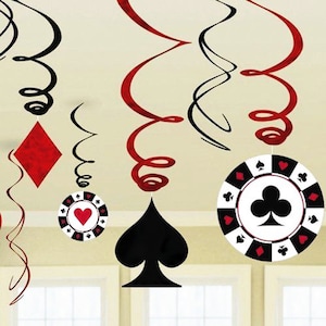 May include: Casino-themed party decorations featuring red and black spiral streamers, diamond, spade, and chip shapes. The chips have heart, spade, club, and diamond symbols. The decorations are hanging in front of a window.